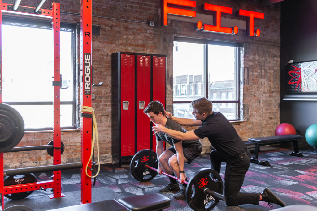 person squatting and weight lifting to help strengthen back and decrease risk of spine injury in kansas city